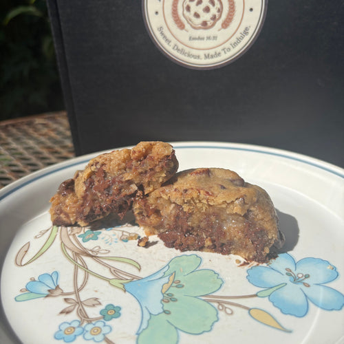 Almond Joy cookie broken in half on a floral plate, showing gooey chocolate and coconut inside