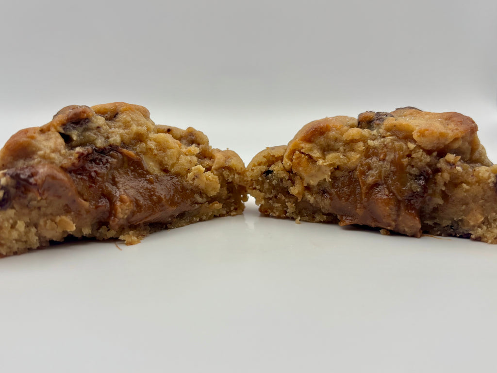 Two halves of a thick, Reeses peanut butter and chocolate filled cookie on a plain white background.