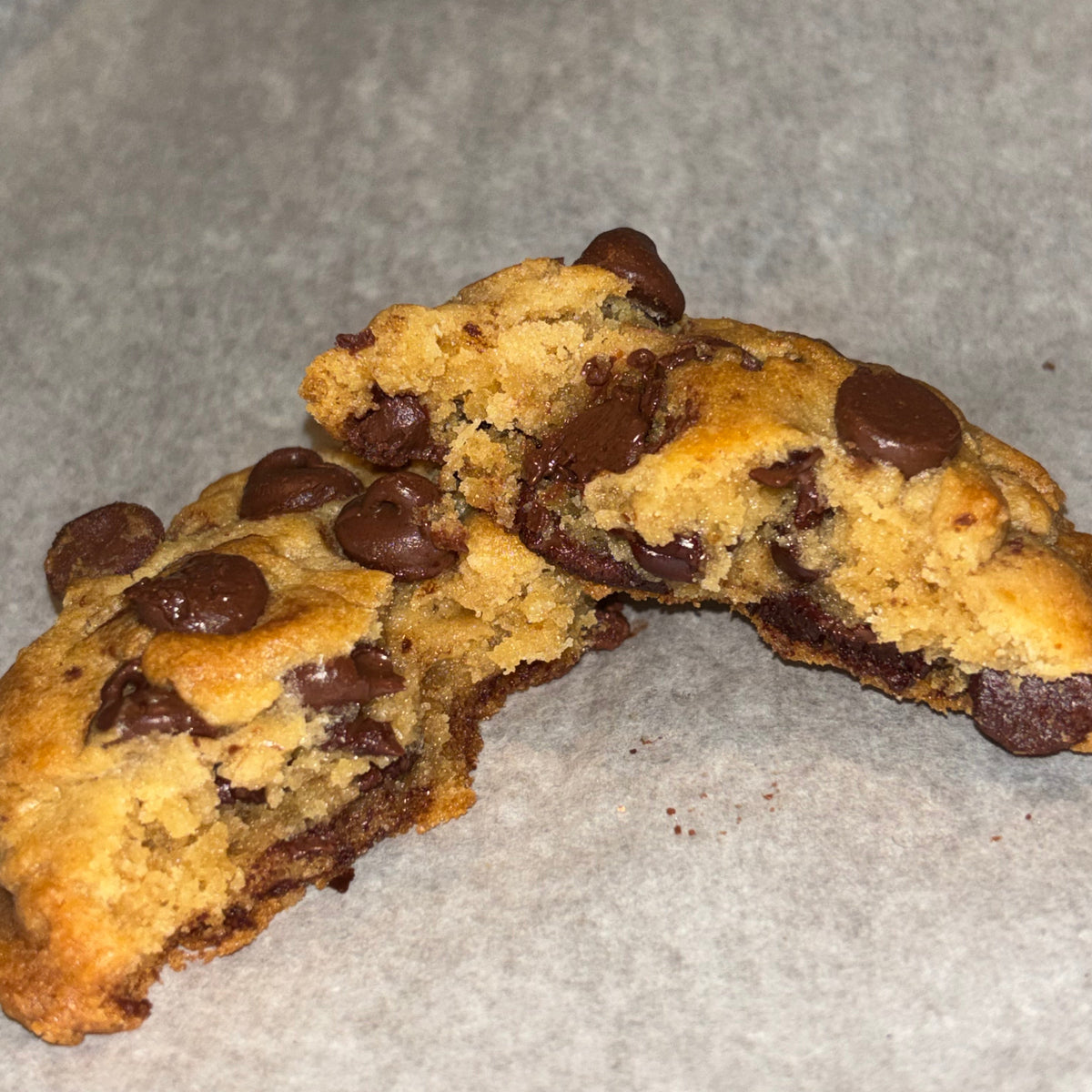Brown butter chocolate chip cookie broken in half, showing gooey melted chocolate chunks inside