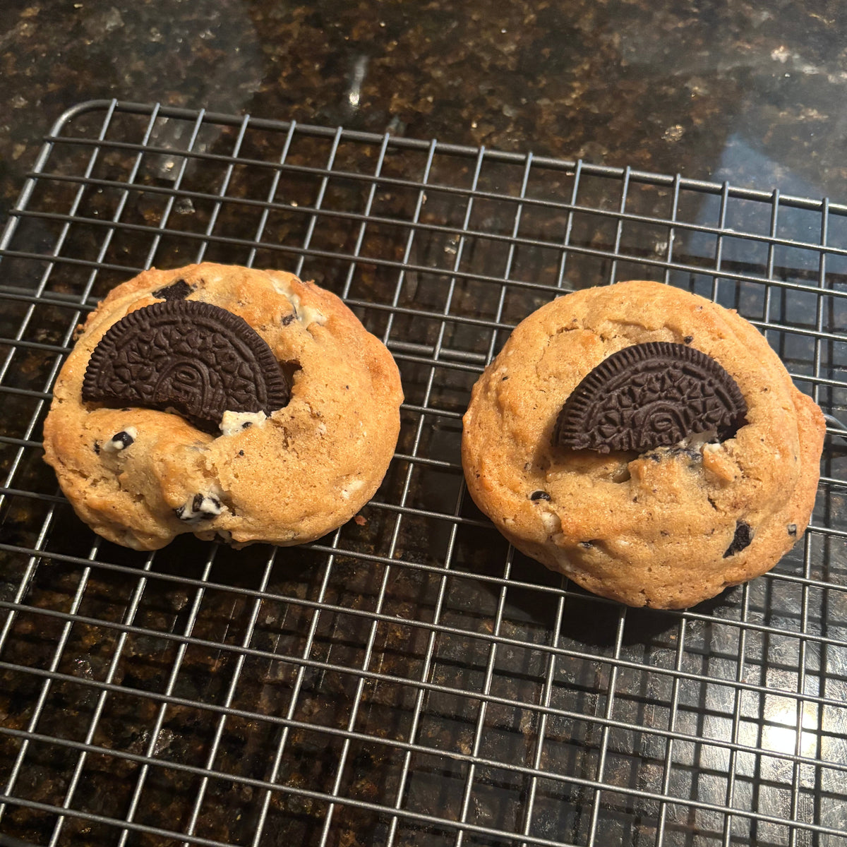 Two Brown Butter Cookies & Cream cookies on a wire cooling rack, each topped with a half chocolate sandwich cookie