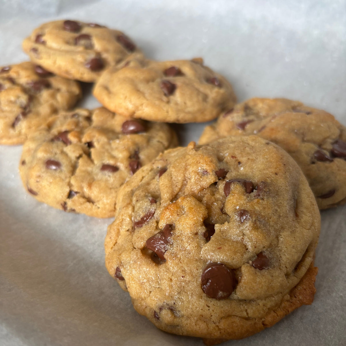 Stack of golden-brown brown butter chocolate chip cookies on parchment paper